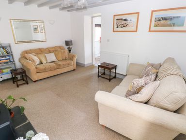 A living room with two sofas a small table and framed pictures on the wall at Barn Court Cottage Narberth Pembrokeshire