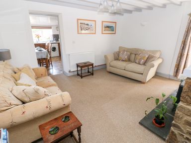 A living room with two sofas a side table plant and a view into a kitchen at Barn Court Cottage Narberth Pembrokeshire