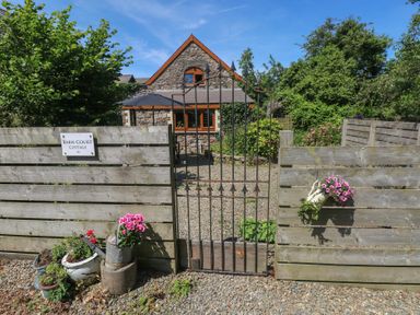 An entrance with a gate and flowers at Barn Court Cottage Narberth, Pembrokeshire