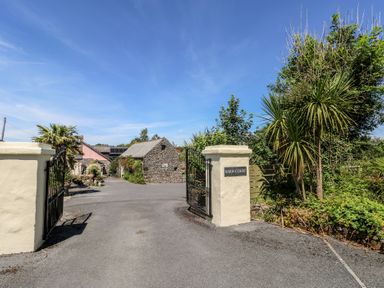 A view of the entrance with gates and palm trees at Barn Court Cottage Narberth, Pembrokeshire