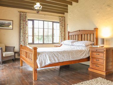 A bedroom with a wooden bed and bedside tables by a window at Stoney Cottage in Narberth Pembrokeshire