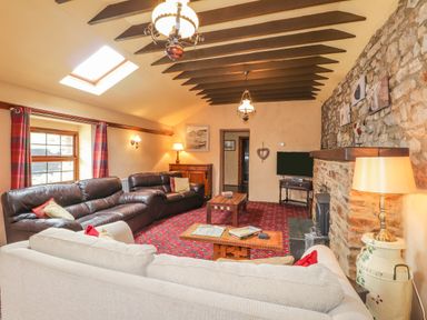 A living room with sofas tables a television and stone fireplace at Stoney Cottage in Narberth Pembrokeshire