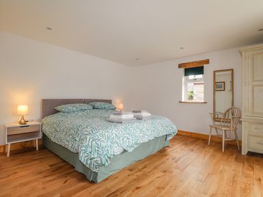 A bedroom with a double bed with patterned bedding a bedside table with a lamp a wooden chair a mirrored wall and a wardrobe at Stoney Cottage in Narberth Pembrokeshire