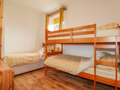 A bedroom with a single bed and a bunk bed with yellow patterned bedding at Stoney Cottage in Narberth Pembrokeshire