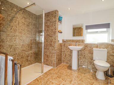 A bathroom with a shower area towel rack sink toilet and window at Stoney Cottage in Narberth Pembrokeshire
