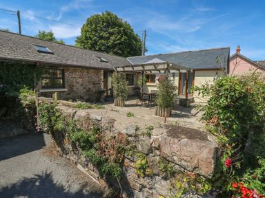 An outdoor patio area with a stone wall and cottage at Stoney Cottage in Narberth, Pembrokeshire