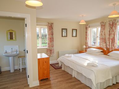 A bedroom with two single beds pushed together beside windows with floral curtains at Goose Cottage in Caledon near Killylea