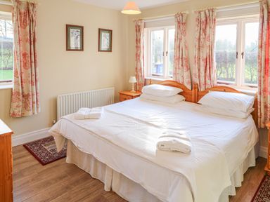 A bedroom with a double bed wooden furniture and floral curtains at Goose Cottage in Caledon near Killylea