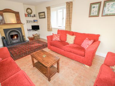 A living room with red sofas a wooden coffee table a fireplace and a small TV at Goose Cottage in Caledon near Killylea