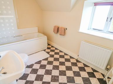 A bathroom with a bathtub sink toilet and checkered floor at Goose Cottage Caledon near Killylea