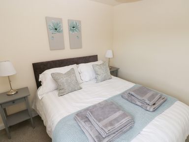 A bedroom with a double bed two bedside tables with lamps and folded towels at Smugglers in Lydstep