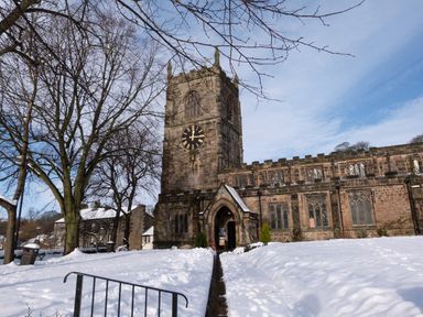 A stone church with a clock tower in a snowy landscape with leafless trees