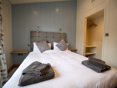 A bedroom with a bed and gray pillows and towels at Wren Lodge in Gargrave