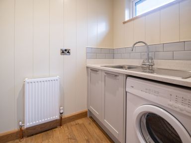 A laundry room with a washing machine sink radiator and cabinets at Wren Lodge in Gargrave