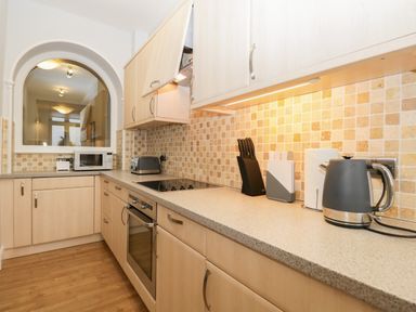 A kitchen with wooden cabinets a microwave a toaster electric kettle and a knife set at Tethera in Bowness-On-Windermere