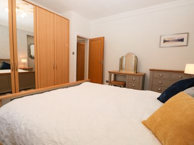 A bedroom with a bed pillows wardrobes a dressing table and a chest of drawers at Tethera in Bowness-On-Windermere