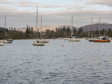 Sailboats anchored on a lake with trees and mountains in the background at Tethera in Bowness-On-Windermere
