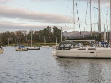 Sailboats anchored on a lake with trees and hills in the background at Tethera in Bowness-On-Windermere