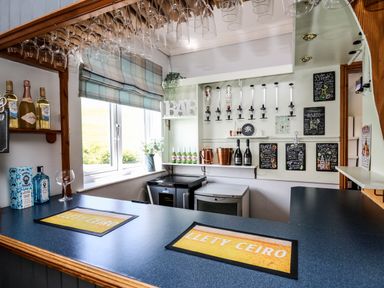 A bar area with bottles wine glasses and drink dispensers at Llety Ceiro in Bow Street Wales