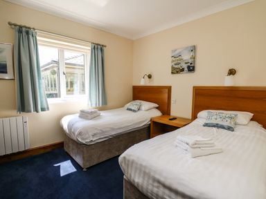 A bedroom with two single beds a window and a nightstand at Llety Ceiro in Bow Street Wales