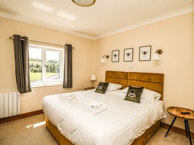 A bedroom with a double bed pillows and towels by a window at Llety Ceiro in Bow Street Wales