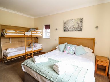 A bedroom with a double bed and bunk beds with pillows and towels at Llety Ceiro in Bow Street Wales