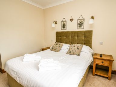 A bedroom with a double bed two cushions two bedside tables and wall lamps at Llety Ceiro in Bow Street Wales