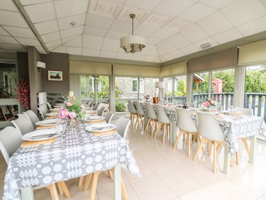 A dining room with tables set with plates glasses and flowers at Llety Ceiro in Bow Street Wales
