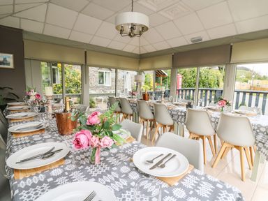 A dining room with tables set with plates cutlery glasses and flowers at Llety Ceiro Bow Street Wales