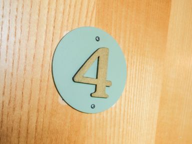 A wooden door with a green circular plaque showing the number 4 at Llety Ceiro in Bow Street Wales