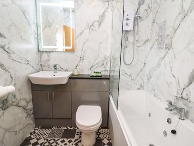 A bathroom with a sink and cabinet toilet and bathtub with shower at Llety Ceiro in Bow Street Wales
