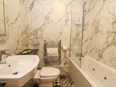 A bathroom with a sink toilet towel rail and a bathtub with a shower at Llety Ceiro in Bow Street Wales