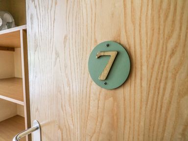 A wooden door with a metal handle and a green circular plaque displaying the number 7 at Llety Ceiro in Bow Street Wales