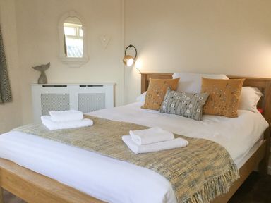 A bedroom with a wooden bed with white linens and decorative pillows at Ty Garth in Benllech