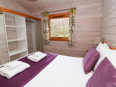 A bedroom with a bed and folded towels by a window with curtains at Barn Owl Lodge in Rhayader