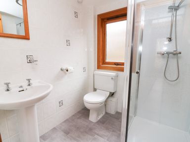 A bathroom with a sink a toilet a shower and a window at Barn Owl Lodge in Rhayader