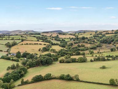 A landscape with fields, trees, and a house at Barn Owl Lodge, Rhayader