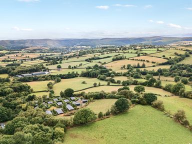 An aerial view of fields and forests at Barn Owl Lodge Rhayader