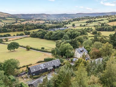 A view of fields and trees near a barn and house at Barn Owl Lodge in Rhayader