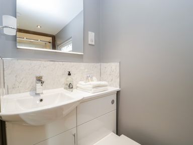 A bathroom sink with a faucet hand soap and folded towels on a vanity unit below a mirror at Deer Lodge in Wimborne Minster