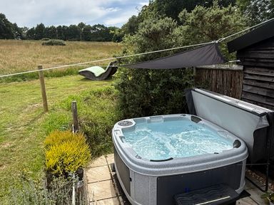 An outdoor area with a hot tub and a hammock at Deer Lodge in Wimborne Minster