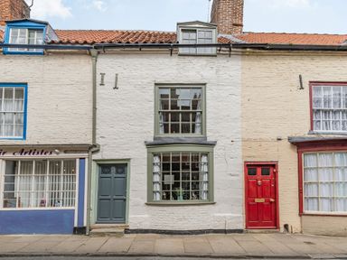 A street view showing a row of old brick buildings with a green door and windows in the center at 48 High Street Bridlington