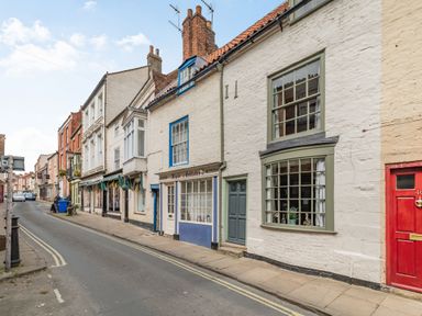 A street with historic buildings and shops including a hairdresser at 48 High Street in Bridlington