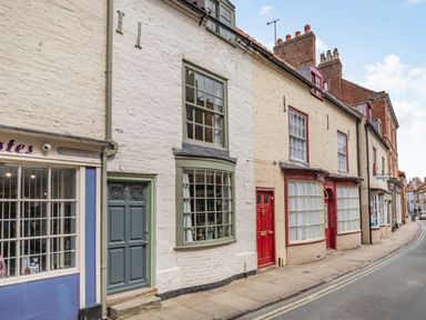 A street view of brick buildings with painted doors and windows at 48 High Street in Bridlington