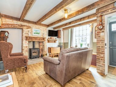 A living room with exposed wooden beams a fireplace a brown armchair and a leather sofa at 48 High Street in Bridlington