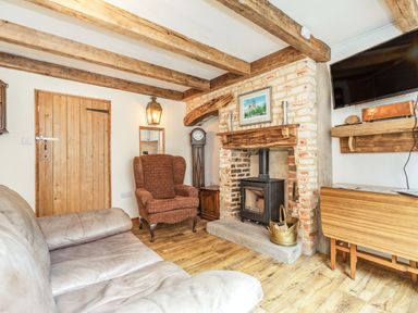 A living room with exposed wooden beams fireplace and armchair at 48 High Street in Bridlington