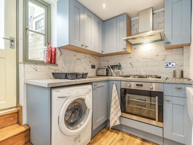 A kitchen with blue cabinets a washing machine oven and stovetop at 48 High Street in Bridlington