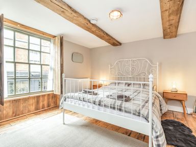A bedroom with a white metal bed frame and plaid bedding by a window with wooden shutters at 48 High Street in Bridlington