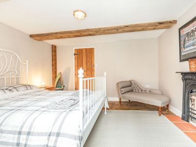 A bedroom with a white metal bed frame a chaise lounge a wooden door and a fireplace at 48 High Street in Bridlington
