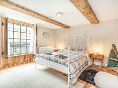 A bedroom with a white metal bed frame wooden bedside tables and a large window with wooden shutters at 48 High Street in Bridlington
